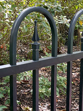 Fence pickets with arched tops and decorative metal finial detail