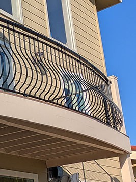 Metal deck spindles installed on curved exterior balcony railing