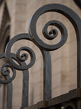 Metal fence pickets with decorative scroll tops in black iron railing