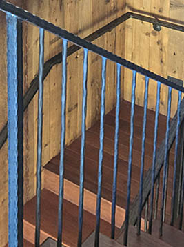 Metal newel posts installed on interior wood staircase railing