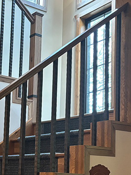 Metal stair spindles installed on interior wood staircase railing