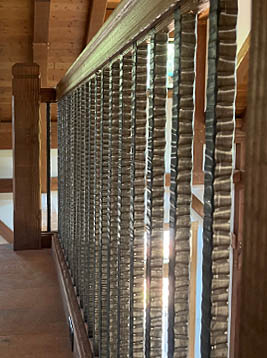 Railing pickets with textured metal balusters in interior wood railing system