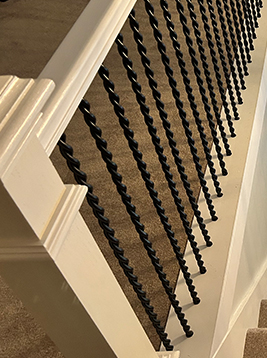 Round metal balusters installed on interior stair railing