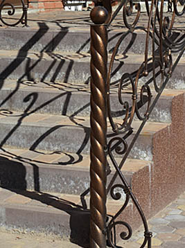Round newel posts with twisted iron design on exterior stone staircase