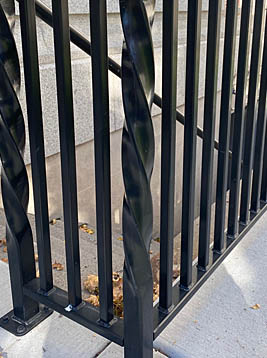 Square iron newel posts installed on exterior railing