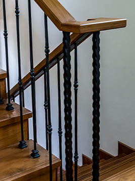Stair newel posts with twisted iron design on interior wood steps