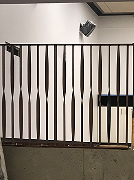 Metal railing spindles with wavy design detail showing installed decorative balusters in interior system