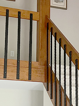 Side mount metal stair balusters detail showing installed decorative spindles on interior staircase railing system