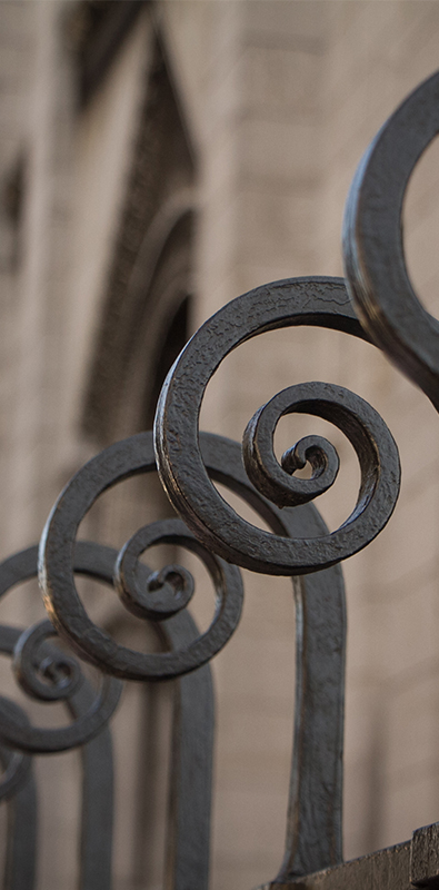 Metal fence pickets with decorative scroll tops in black iron railing