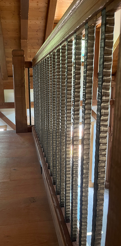 Railing pickets with textured metal balusters in interior wood railing system