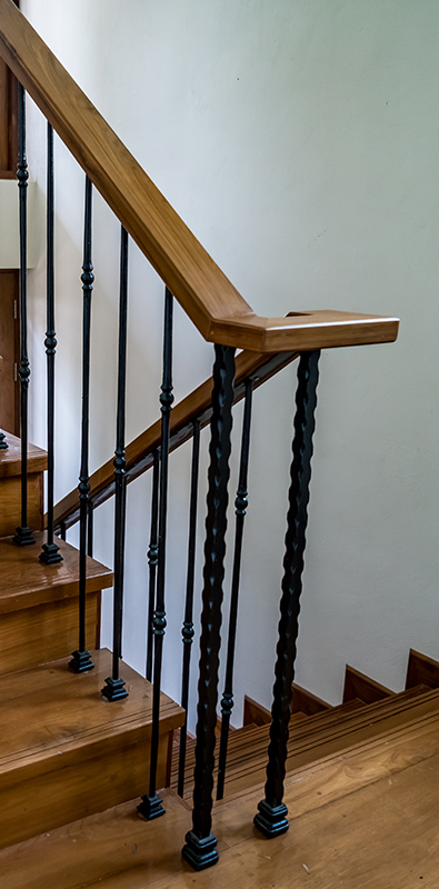 Stair newel posts with twisted iron design on interior wood steps