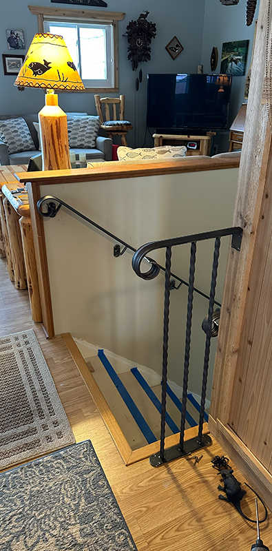 Stair pickets with twisted iron balusters installed on wood staircase railing